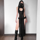 Model draagt een zwarte gebreide lange jurk met capuchon, een gedurfde split en stijlvolle laarzen.