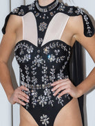 Body de pedrería con capa que presenta pedrería brillante y un diseño dramático de capa.