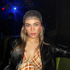 Pañuelo negro con pedrería usado por una mujer con maquillaje elegante en un ambiente vibrante de festival.