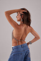 Top court bohème en maille métallique argentée fait main avec pendentifs en coquillage, dos nu et lien noué autour du cou.