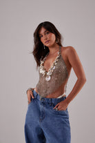 Haut court bohème en maille métallique argentée fait main avec pendentifs en coquillage naturel, porté par un mannequin.