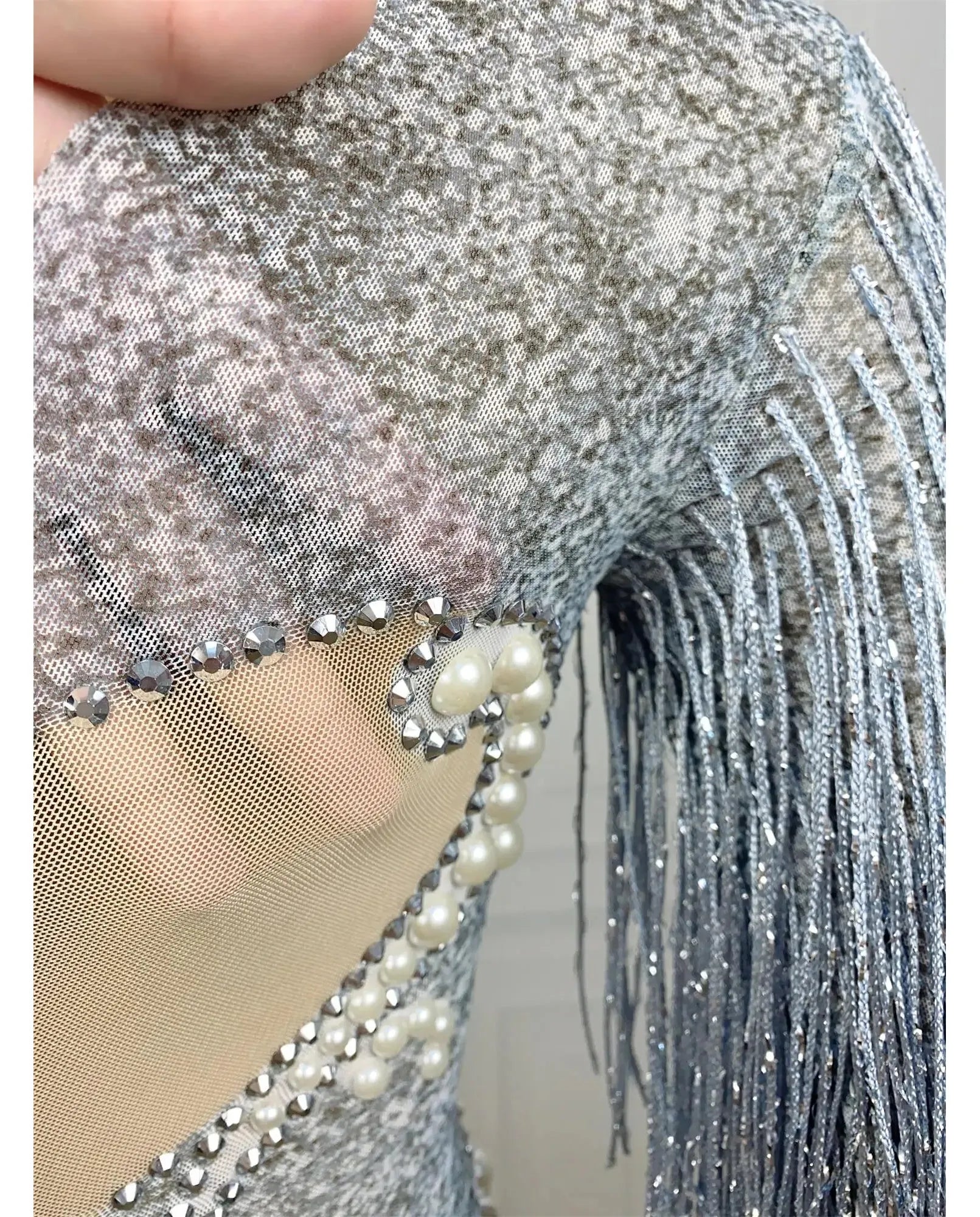 primo piano di body a maniche lunghe con nappe, strass, perle, paillettes argento e perle