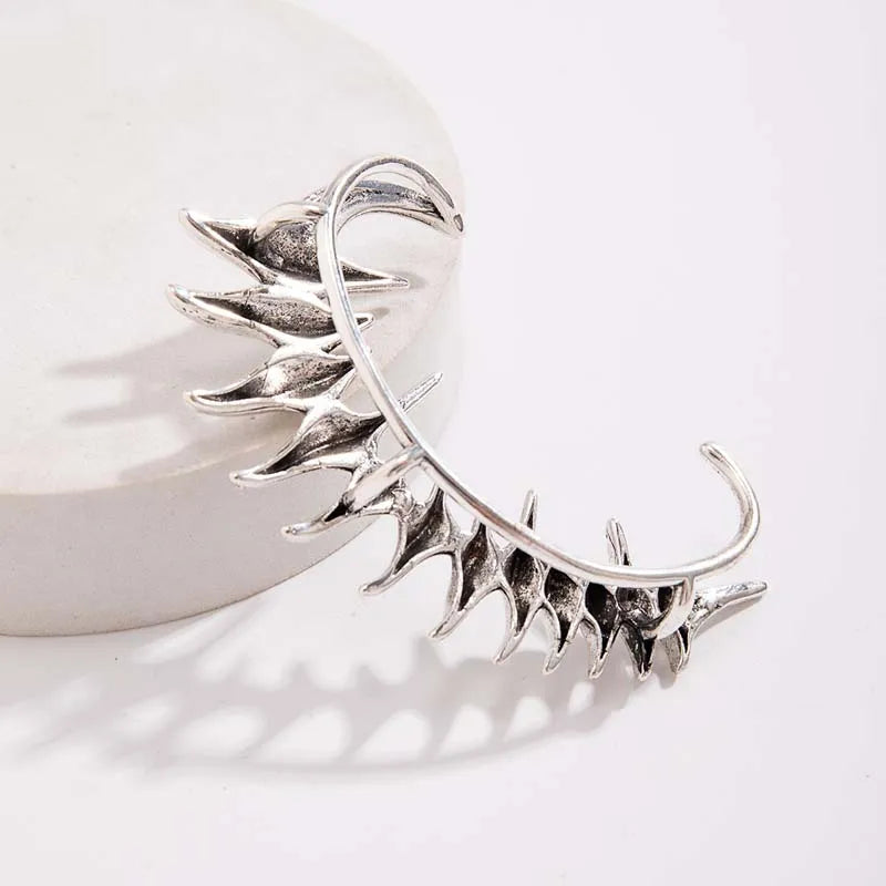 Ear cuff in metallo argento Cyberpunk con punte angolari affilate in un design a colonna vertebrale biomeccanica, avvolgente l'intero orecchio.