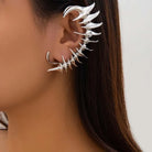Ear cuff in metallo argento Cyberpunk, un avvolgimento completo dell'orecchio con punte biomeccaniche appuntite e angolari a forma di spina.