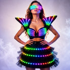 Model wearing a black LED tutu bra set with glowing rainbow lights on the bra, shoulder pieces, skirt, and visor.