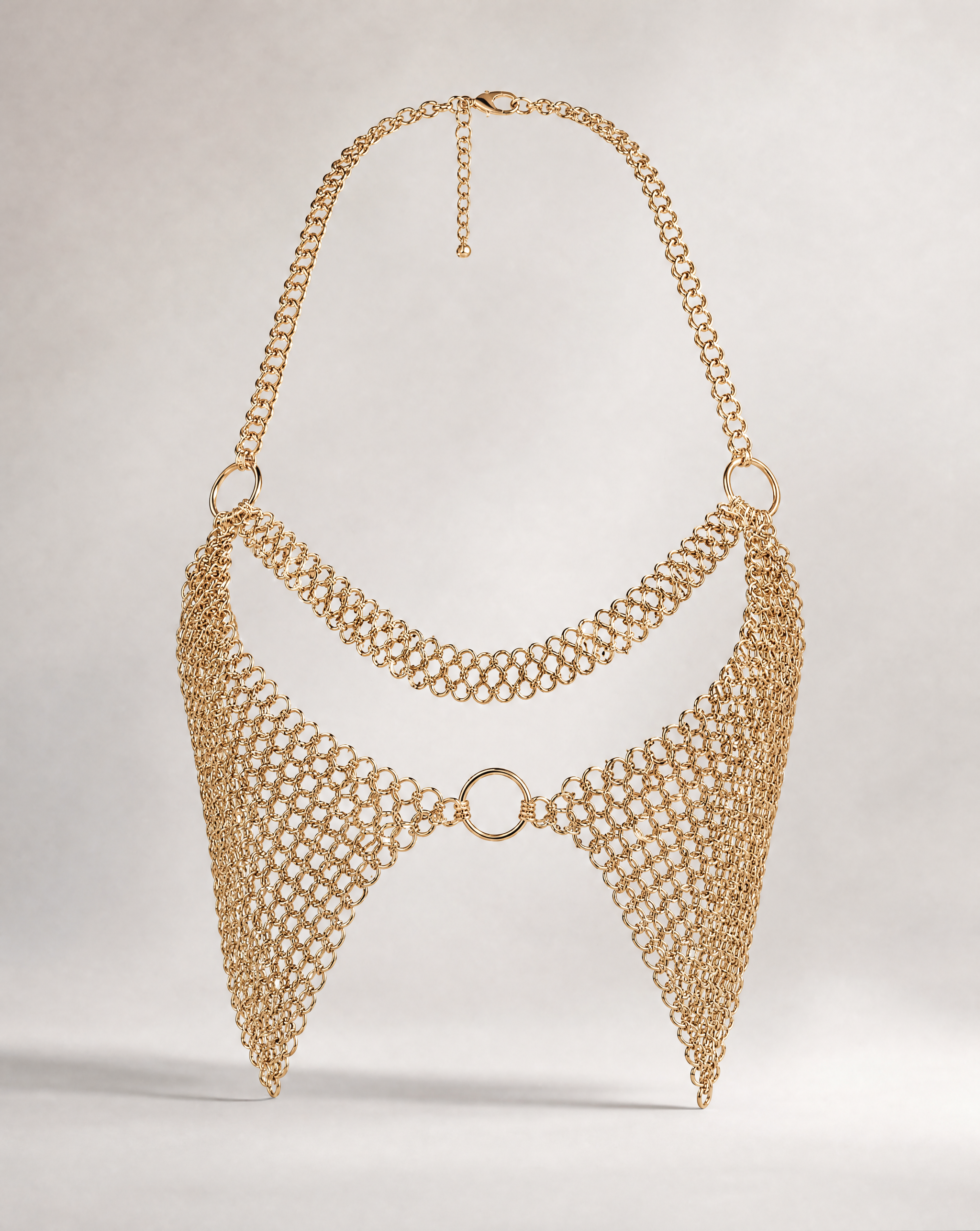 Gold metal chain bra with intricate interlocking rings, halter neck, and central ring detail.