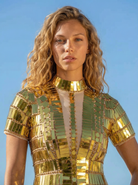 Vestido de lentejuelas espejo reflectante dorado con cuello alto y escote transparente, llevado por una mujer.