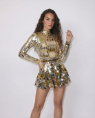 Woman in a gold and silver mirrored sequin mini dress with long sleeves and a high neck.
