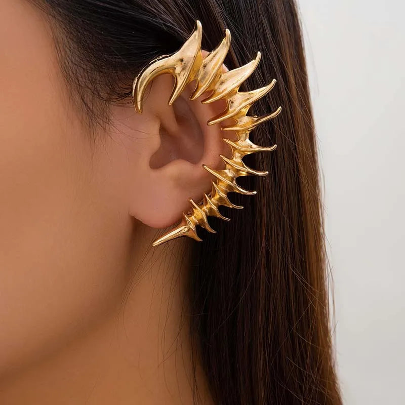 Gold full ear cuff with sharp, angular spikes in a biomechanical spine design, worn on a left ear.