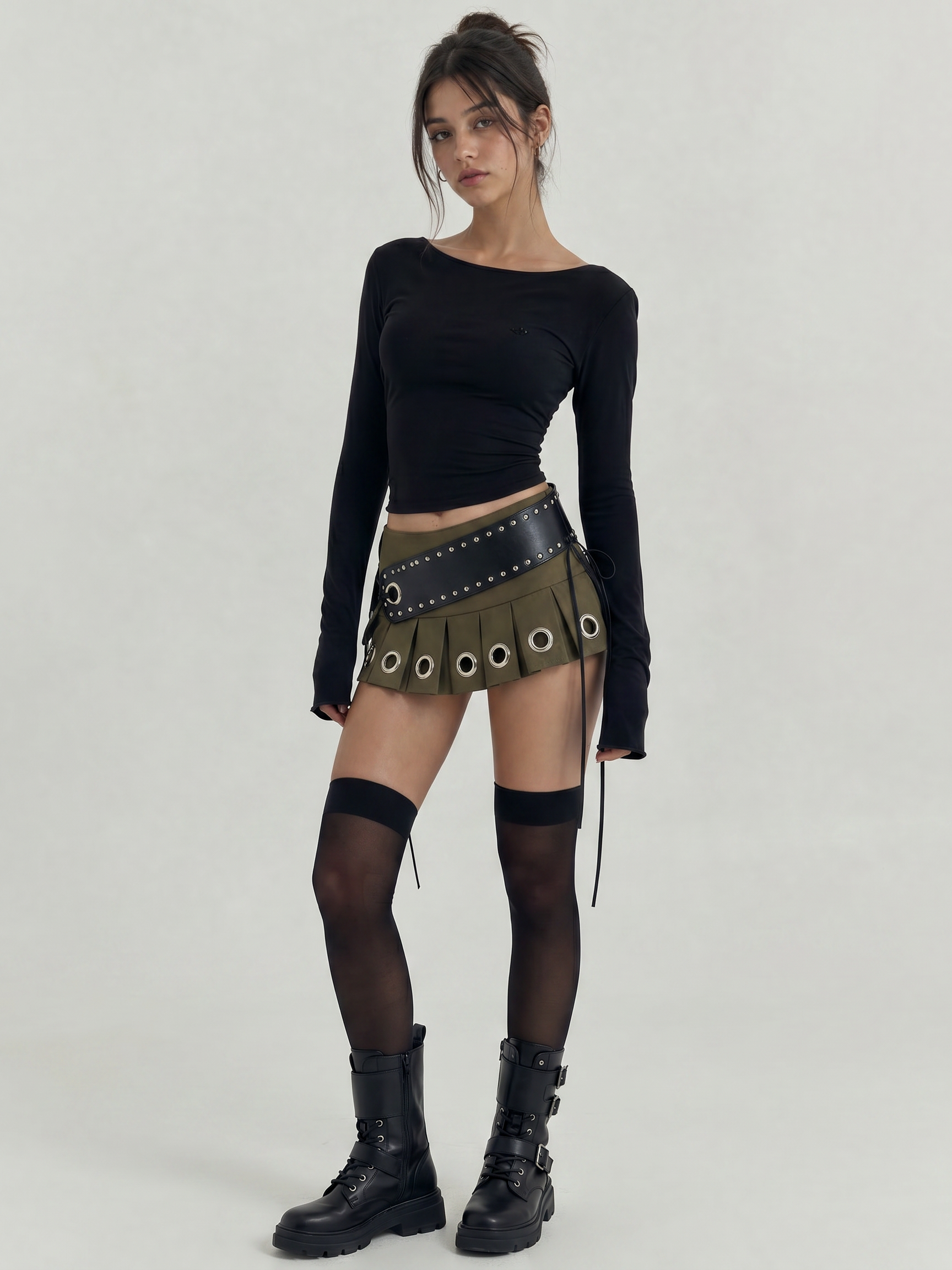 Green pleated mini skirt with large silver grommets and a wide black studded belt.