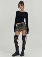Green pleated mini skirt with large silver grommets and a wide black studded belt.