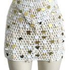 conjunto de top sin mangas con cuello halter y falda en blanco con detalles de lentejuelas doradas