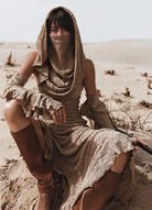 Vestido con capucha de punto jacquard en un paisaje arenoso, con un diseño suave y aireado con mangas y máscara.