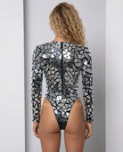 Kayla Mirror Rhinestone Bodysuit, a long-sleeved, high-cut silver bodysuit with reflective mirror pieces and a back zipper.