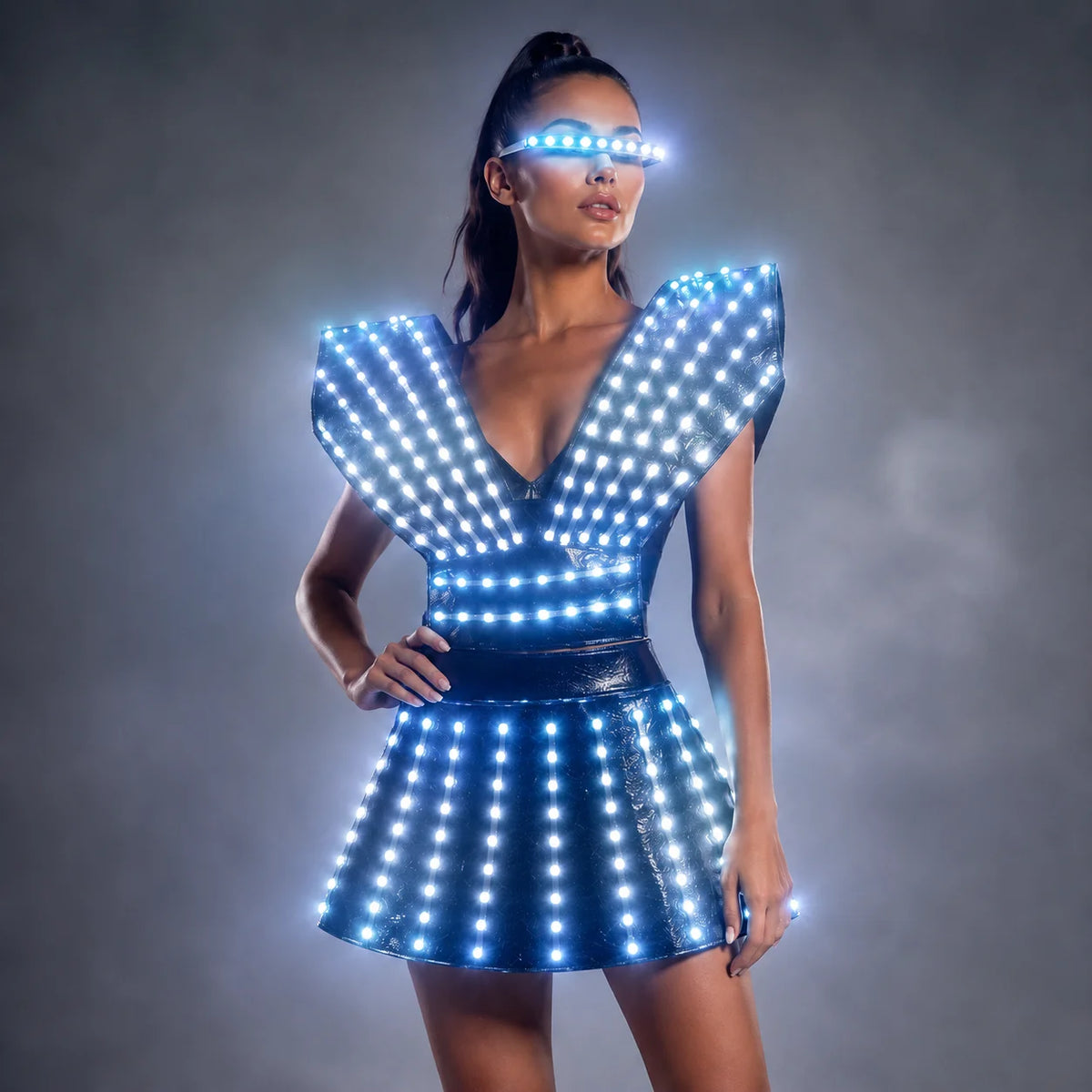 Model wearing a futuristic black LED dress with glowing blue lights and matching visor on a grey background.