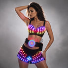 Model wearing a black LED light-up bra, belt, and shorts set with multicolored glowing lights and remote control.