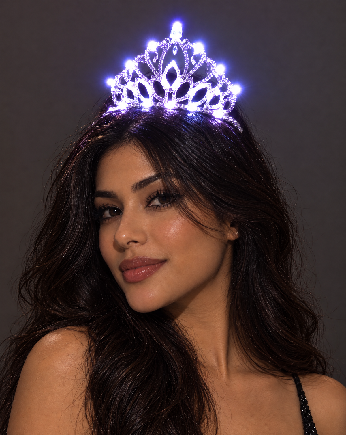 Woman wearing a glowing LED rhinestone tiara with intricate crystal detailing against a dark background.