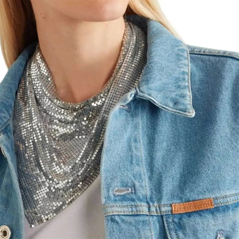 Silver liquid metal mesh scarf draped over a woman's neck, worn with a denim jacket.