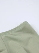 Detail eines grünen Crop-Tops mit langen Ärmeln und Minirock