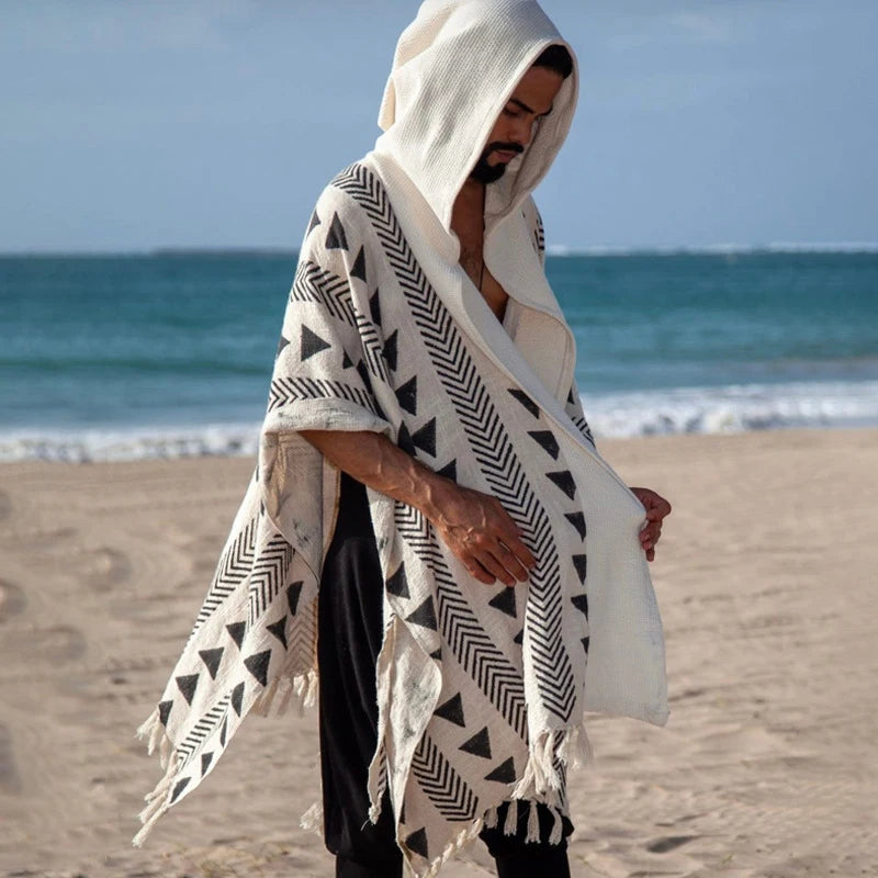 Men's Tulum Fringe Cardigan in cream polyester with black geometric patterns and a hood, worn on a beach.