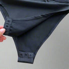 Close-up of the fastened bottom of a Mesh Patchwork Bodysuit showing its sleek mesh fabric.