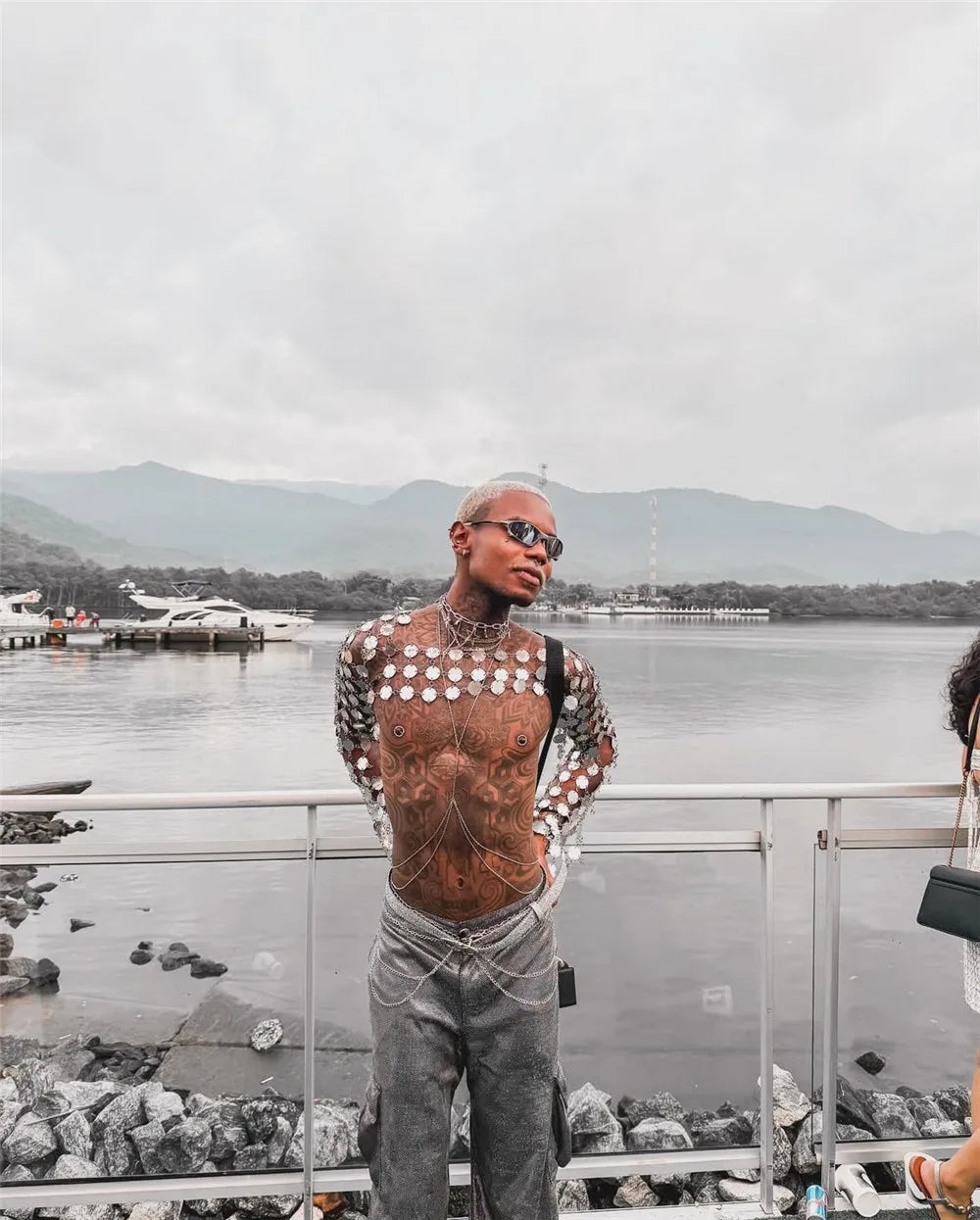 metal chain disc crop top side-profile with tattoos outdoors against water backdrop