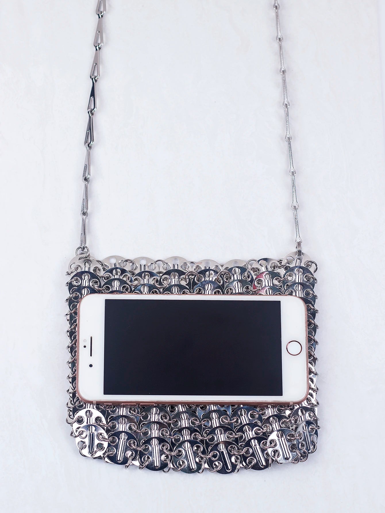 Metallic Sequin Bag featuring a shiny, intricately designed surface, styled with a mobile phone.