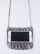 Bolso de lentejuelas metálicas con una superficie brillante y de diseño intrincado, estilizado con un teléfono móvil.