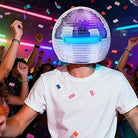 Adult wearing a 40cm Mirror Disco Ball Helmet with built-in blue lights, surrounded by confetti at a party.