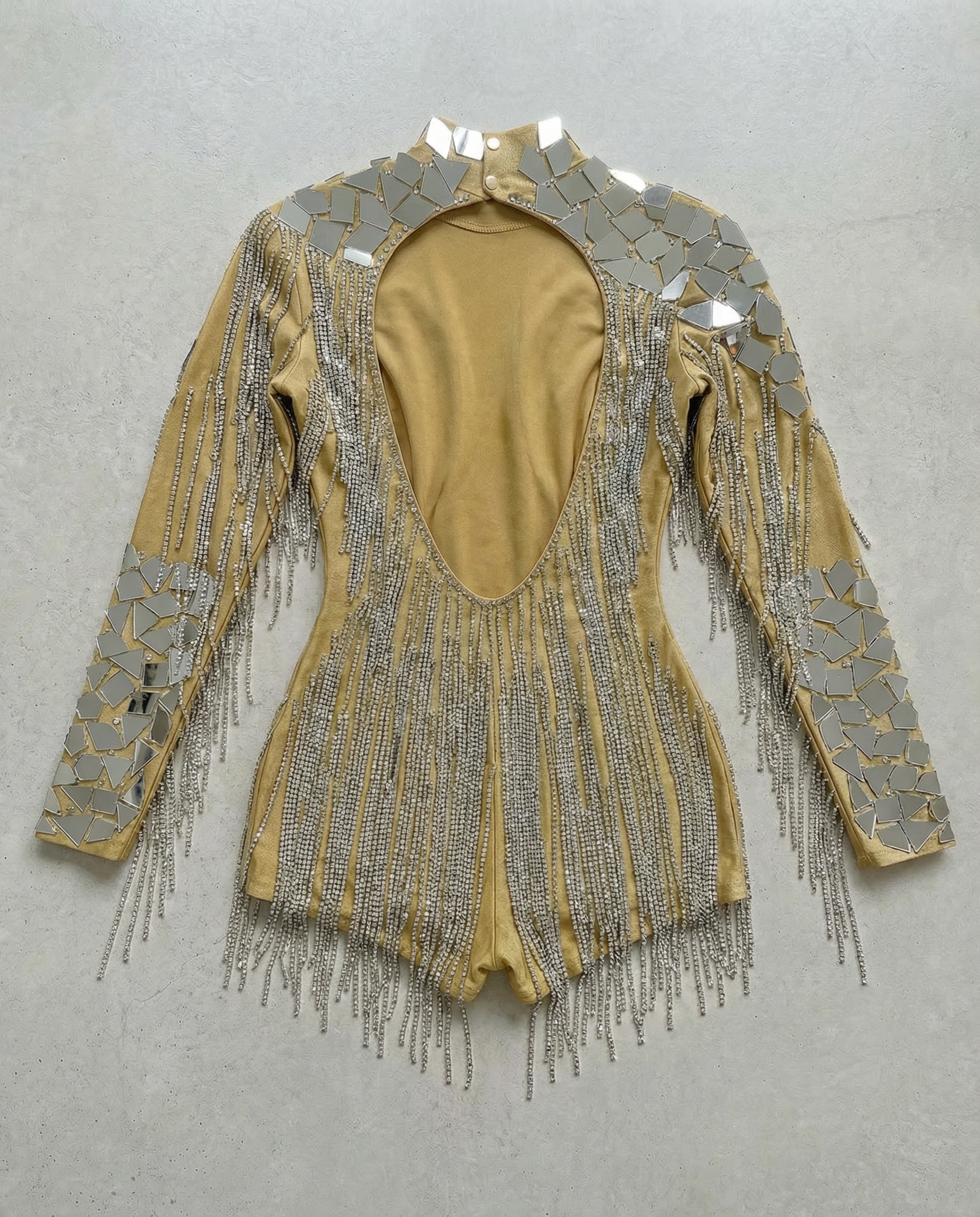 Gold backless bodysuit with mirror panels and rhinestone chain fringe.