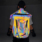 Multicolor reflective techno vest with a large hood and black strap details, worn by a person from behind.