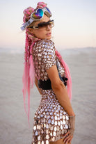 Vestido de fiesta con lentejuelas metálicas color champán, cabello rosa y gafas de sol extragrandes en un entorno desértico.