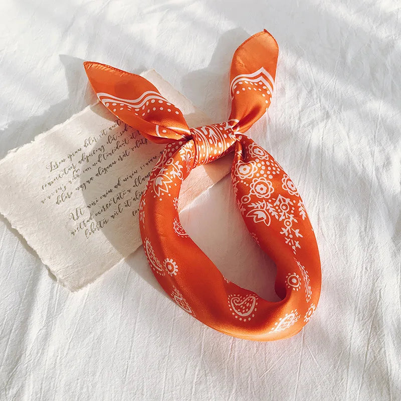 Satin Bandana in vibrant orange with decorative white patterns, perfect for versatile styling.