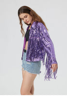 Purple metallic sequin jacket with long fringe sleeves worn over a black top and denim shorts.