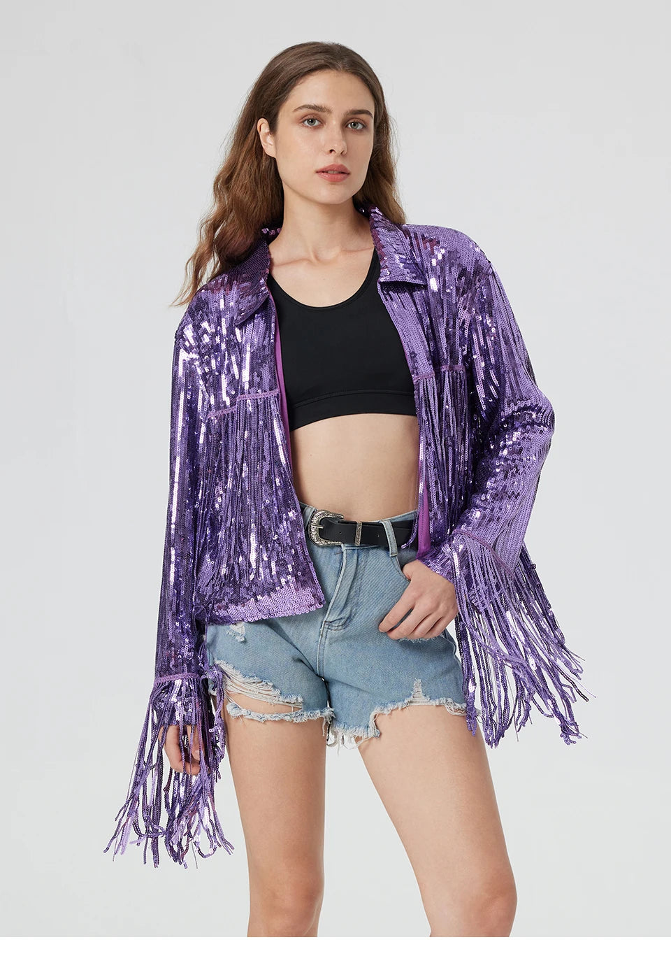 Purple metallic sequin jacket featuring long fringe trim on the sleeves and hem, worn over a black top and denim shorts.