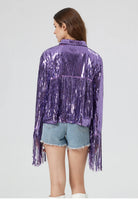 Purple metallic sequin jacket with long fringe detailing on the back and sleeves, worn over denim shorts.