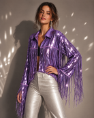 Model wearing a metallic purple sequin jacket with long fringe sleeves and a collar, paired with silver pants.