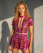 Woman in a fuchsia and magenta sequin mini dress with a sheer neckline and short sleeves.