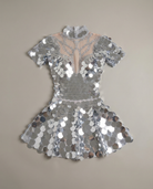 Vestido mini de lentejuelas plateado con espejo y pedrería, con escote de malla transparente y mangas cortas.