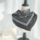 Bandana de satén con un intrincado diseño de cachemira en blanco y negro, perfecto para opciones de estilo versátiles.