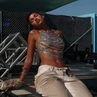 Model draagt een Sequin Metal Chest met metalen kettingen op een festival, die licht reflecteren.