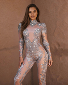 Model in a silver rhinestone metallic jumpsuit with sheer panels and intricate embellishments.