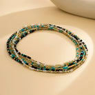 Cadena de cintura con pequeñas cuentas de colores que presenta cuentas vibrantes en negro, dorado, turquesa y blanco.