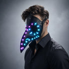 Black faux-leather plague doctor mask featuring glowing blue and purple LED lights, worn by a man in a black shirt.