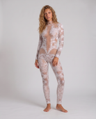 Model wearing a white long-sleeve jumpsuit featuring intricate lace patterns, hand-glued rhinestones, and sequin embellishments.