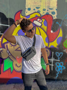 Persona usando una Riñonera Impermeable frente a un fondo de graffiti colorido, perfecta para festivales.