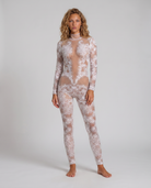 Model wearing a white long-sleeve jumpsuit featuring intricate lace patterns, hand-glued rhinestones, and sequin accents.