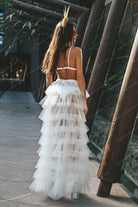 Modelo vistiendo falda envolvente de tul transparente con volantes en capas blancas y estratificadas al aire libre.