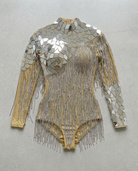 Gold backless bodysuit with mirror panels and cascading rhinestone chain fringe.