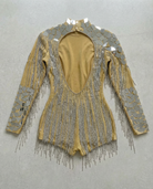 Gold backless bodysuit with mirror panels and rhinestone chain fringe.
